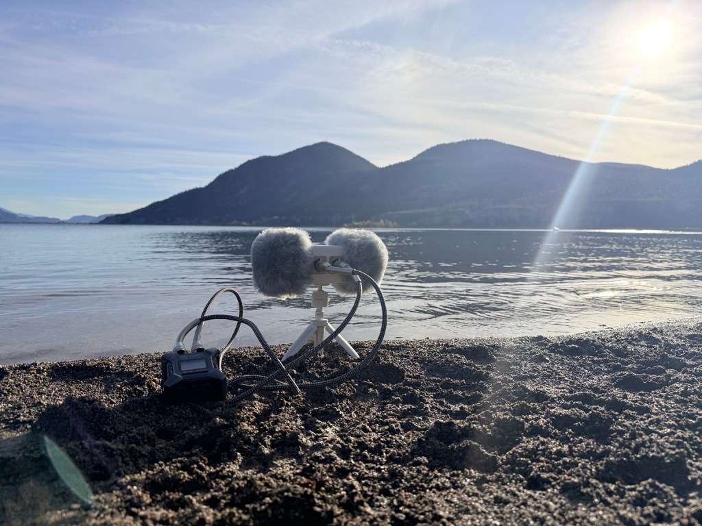 Binaural microphone and portable recorder on a lakeshore in the Okanagan, with mountains across the water.